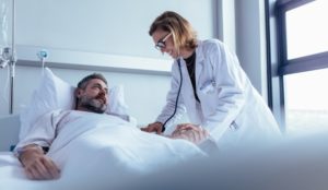 Man in hospital bed after a car accident injury with doctor attending to injuries.