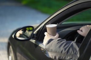 Man on his way to work driving holding a cup of coffee