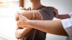 Therapist treating an injured man by rotator cuff stretching method